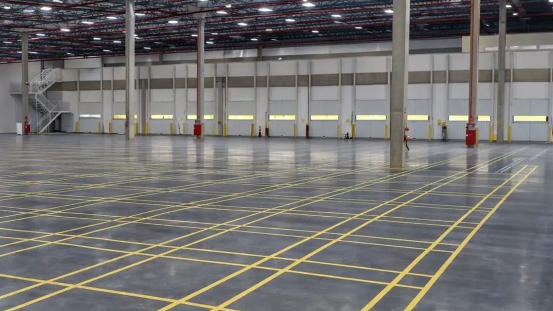 Interior de centro logístico com demarcação de piso, docas e estrutura metálica